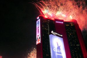 Resorts World の屋上から打ち上げられる花火。手前はセリーヌ・ディオンのコンサートを告げる広告塔。