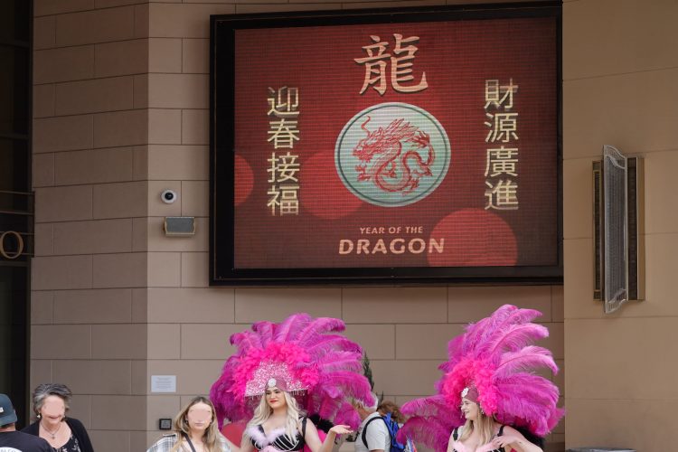 辰（竜）年を意味する「YEAR OF THE DRAGON」の文字と竜が描かれたディスプレイ。手前はラスベガスのシンボル的存在のショーガール。