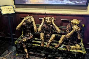 この店の名物「見ざる聞かざる言わざる」が入口に鎮座。左上に「No Monkey Business！」（インチキ商売は無し）と書かれている。