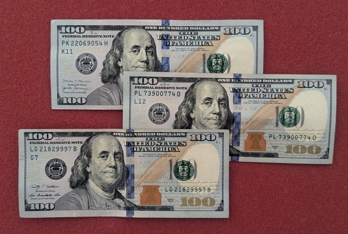新100ドル紙幣。１番下の１枚は裁断ズレが激しすぎ、上下で余白部分の幅が大きく異なっている。